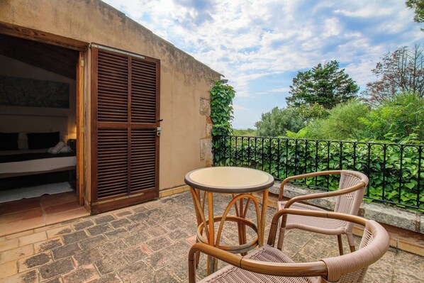 A balcony with wicker furniture and a view of greenery.