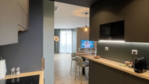 Moderni keittiö, jossa on sisäänrakennettu uuni, kahvinkeitin ja seinälle asennettu televisio.