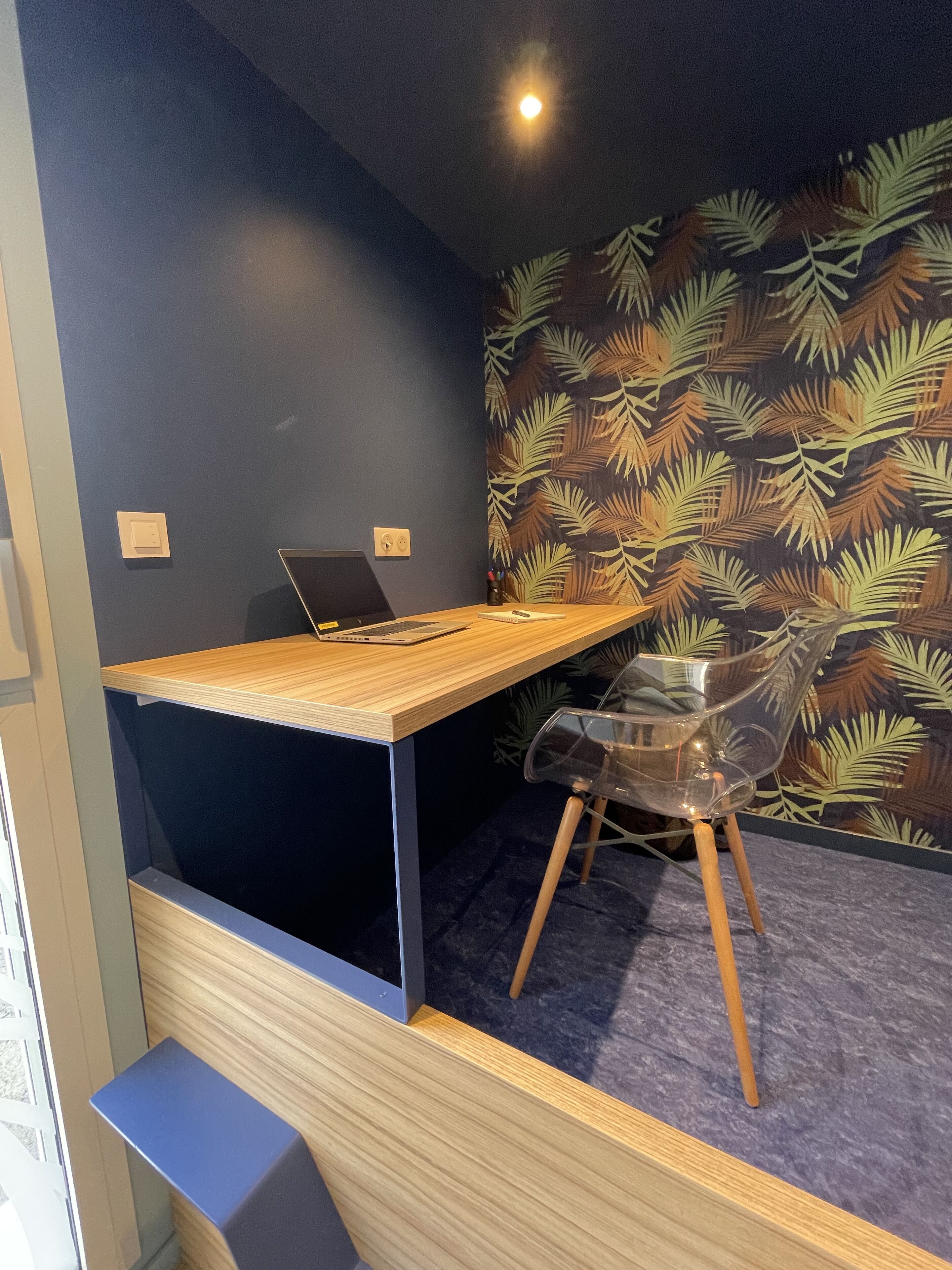 Et moderne arbejdsområde med et træskrivebord, en bærbar computer og en klar plastikstol.