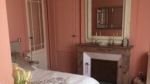 Ein Schlafzimmer mit einem Bett, einem Spiegel, einem Kamin und einem runden Tisch.