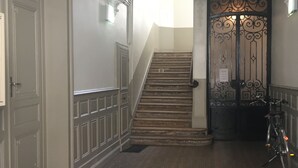 Ein Korridor mit gemustertem Teppich, einer Treppe und einem schmiedeeisernen Gitter.