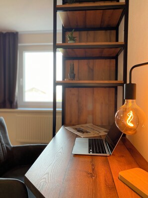 Et træskrivebord med en bærbar computer, en lampe og en notesbog.