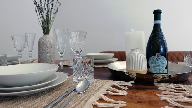A dining table set with clear glassware, plates, a candle, and a bottle of wine. - Bohème Historic | City | 100m2 | Netflix (Landshut)