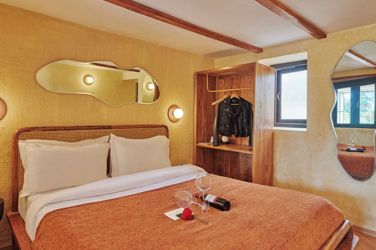 Ein Hotelzimmer mit einem Bett, einem Holzschrank, einem Spiegel und einem Fenster.