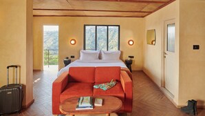 Habitación de hotel con cama, sofá rojo, una mesita, maleta y puerta.