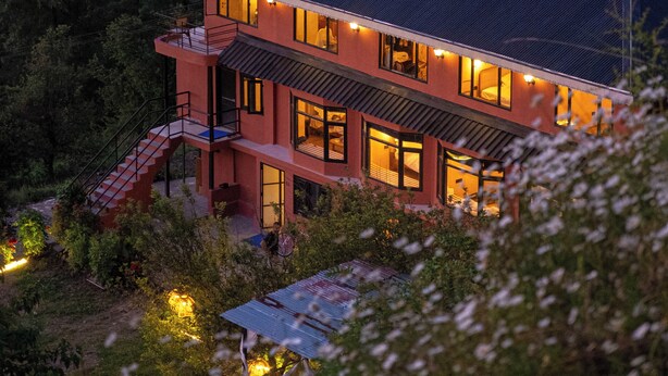 Una casa moderna de dos plantas con techo plano, ventanas amplias y una escalera que conduce al nivel superior.