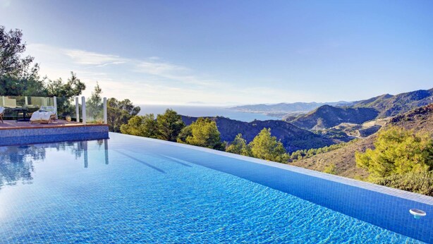 An infinity pool with a clear view of the surrounding landscape, including hills and trees. - Elegant Luxury Villa with Stunning Mediterranean Views (La Herradura)
