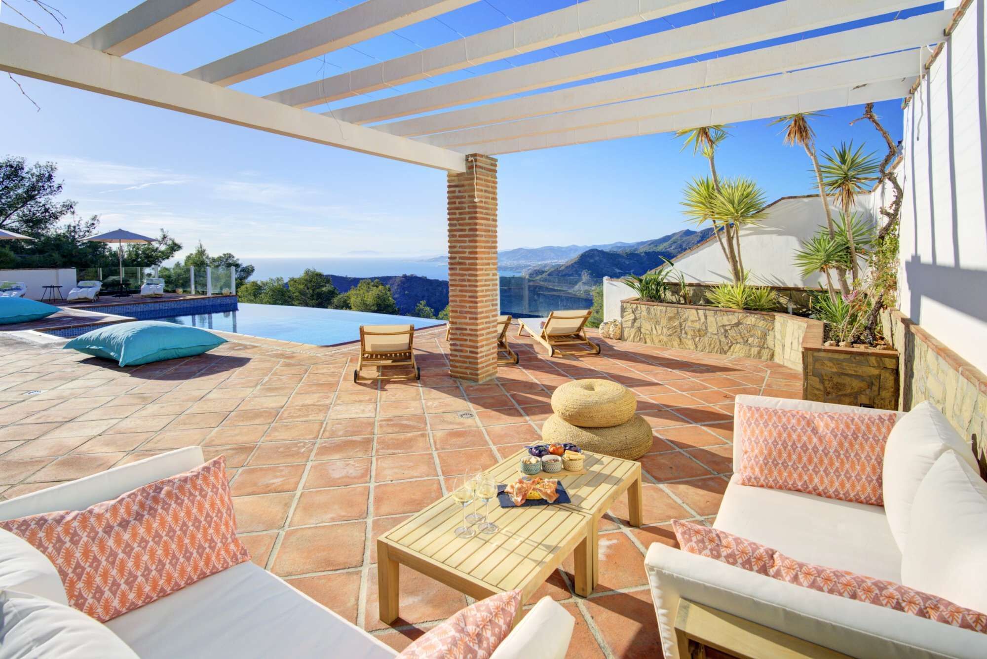Una terrazza con piscina, area relax esterna e vista sulle montagne.