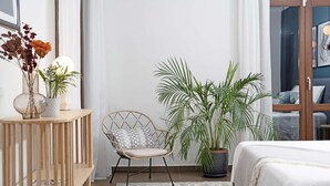 A bedroom with a bed, a chair, a small table with a vase, and a large potted plant. - Elegant Luxury Villa with Stunning Mediterranean Views (La Herradura)