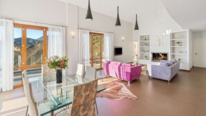 A spacious living room with a glass dining table, a pink sofa, a grey sofa, and a fireplace. - Elegant Luxury Villa with Stunning Mediterranean Views (La Herradura)