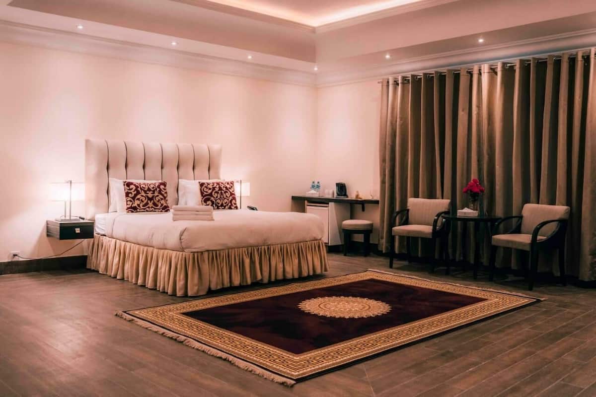 Une chambre spacieuse avec un grand lit, un bureau et deux chaises.