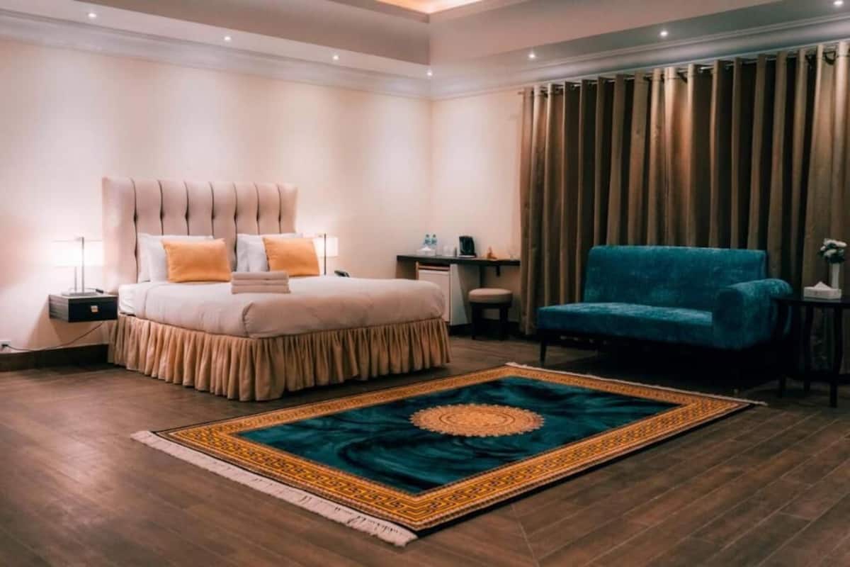 Une chambre d’hôtel avec un lit, un bureau, une chaise et un grand tapis.