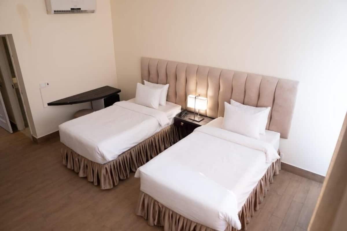 Une chambre d’hôtel avec deux lits, une table de chevet, une lampe et une petite table.