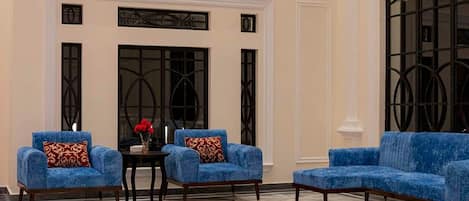 A spacious lobby with a high ceiling, a large blue sofa set, a patterned rug, and a fireplace.