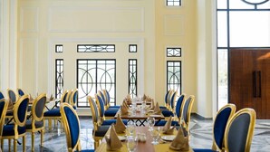 Ein formeller Speisesaal mit langen Tischen, blau gepolsterten Stühlen und goldenen Akzenten.