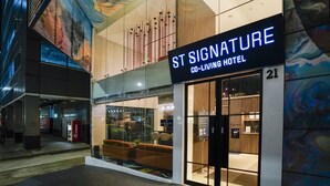 The exterior of St Signature Co-Living Hotel, featuring a modern design with glass walls and a visible interior seating area. - ST Signature Bugis Middle (Singapore)