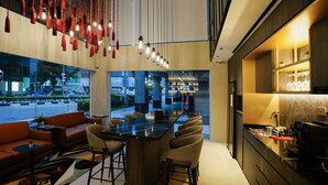 A modern bar area with a long counter, bar stools, and hanging red lanterns. - ST Signature Bugis Middle (Singapore)