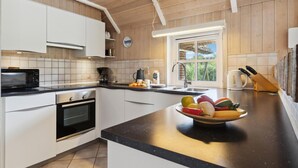 A modern kitchen with white cabinets, a black microwave, a built-in oven, and a large window providing natural light. - 4 bedroom gorgeous home in Rømø (Rømø)