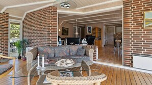 A spacious living area with a brick wall, a glass coffee table, a sofa, and a dining table. - 4 bedroom gorgeous home in Rømø (Rømø)