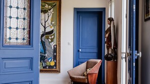 A hallway with a wooden herringbone floor, a blue door, and a painting on the wall. - Eclectic Eminence, by Veeve (Paris)