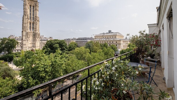 A balcony with a view of a historic tower and a large building with a dome. - Eclectic Eminence, by Veeve (Paris)