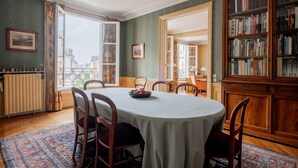 A dining area with a round table, chairs, a buffet, and a bookshelf. - Mellow Grace, by Veeve (Paris)