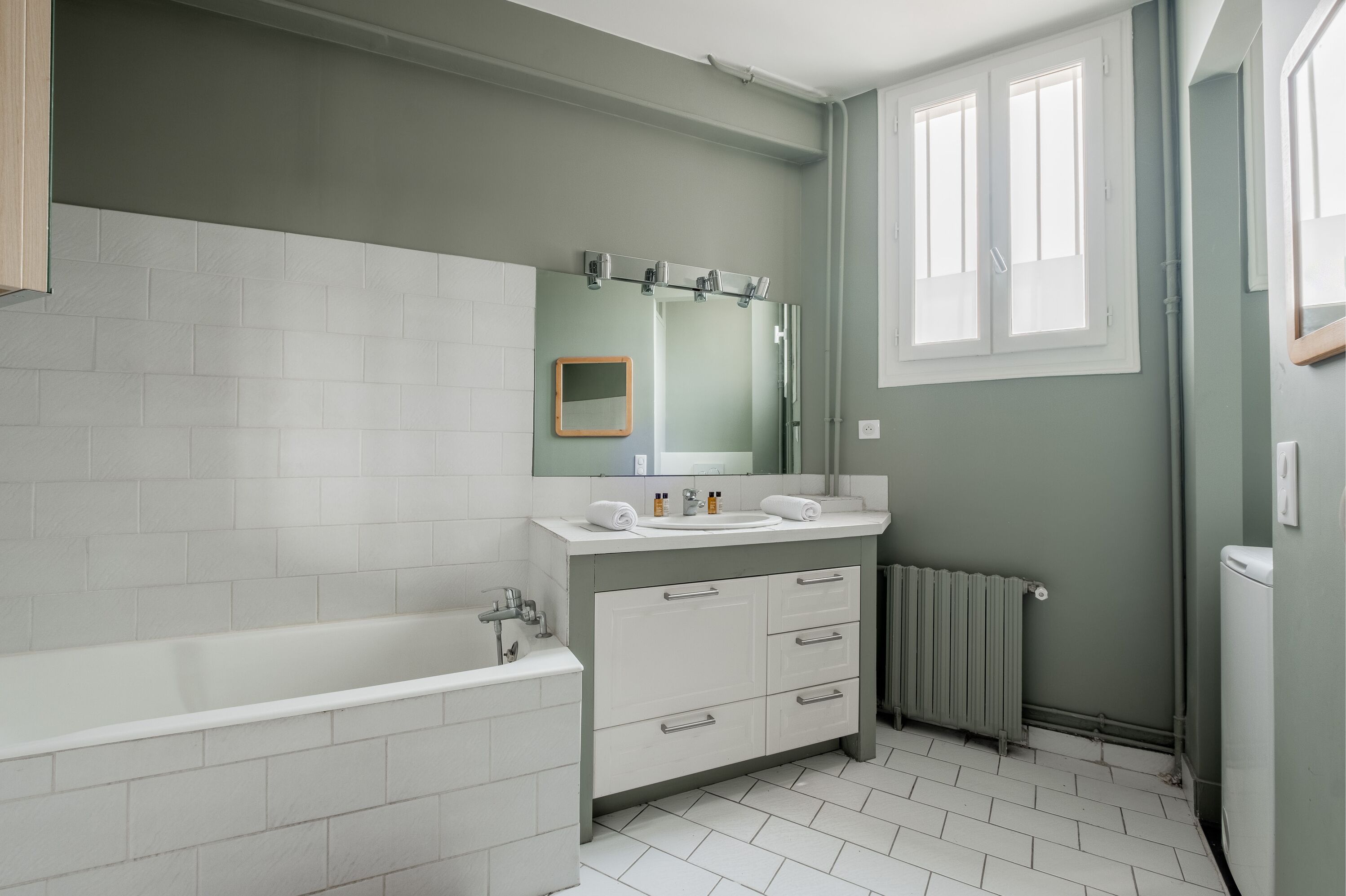Un baño con bañera, lavamanos y espejo.