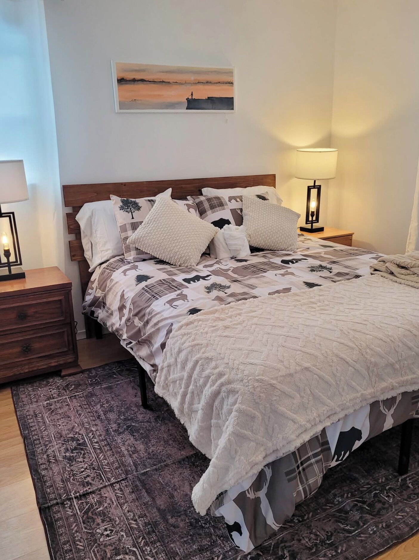 A neatly made bed with a patterned bedspread, a wooden headboard, and a bedside lamp.