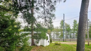 A small white cabin surrounded by dense pine trees and a wooden fence. - Mazinaw Lakeside RV Park & Campground (Cloyne)