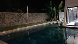 Ein Schwimmbecken mit Steinmauer und Topfpflanzen.
