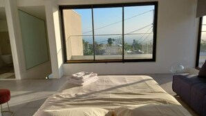 Ein Schlafzimmer mit großem Fenster, einem Bett, einer Couch und einem kleinen Tisch.