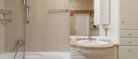 A modern bathroom with a bathtub, a shower, and a sink.