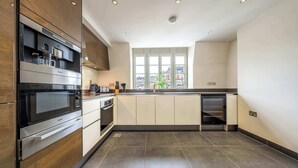 Une cuisine moderne dotée d’appareils électroménagers intégrés, d’une grande fenêtre et offrant une vue sur la ville.