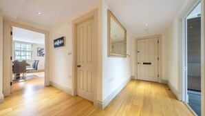Un couloir doté d’un plancher en bois, de portes blanches et d’un grand miroir accroché au mur.