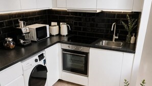 Une cuisine moderne avec des meubles blancs, un plan de travail noir et un coin repas agrémenté d’assiettes, de verres et de couverts.