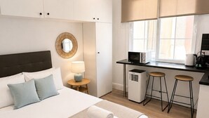 Une chambre d’hôtel moderne équipée d’un lit, d’un bureau, d’un four à micro-ondes et d’une machine à café.