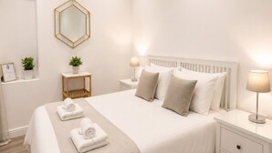 Camera da letto moderna con un letto grande, comodini, uno specchio e un tavolino con una pianta.