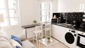 Une cuisine moderne avec des meubles blancs, un plan de travail noir et un lave-linge.
