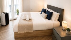 Ett modernt hotellrum med en stor säng, sängbord, en värmare och utsikt genom fönstret.