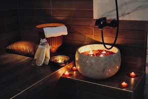 A spa room with a stone basin, candles, a towel, and a massage chair. - Perla Blanca Hotel (Trabzon)