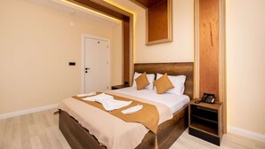 Une chambre d’hôtel avec un lit en bois, une table de chevet avec un téléphone et une porte.