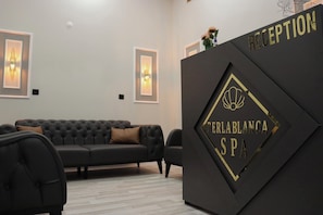 Uma área de recepção com um balcão preto, um sofá preto e quadros nas paredes.