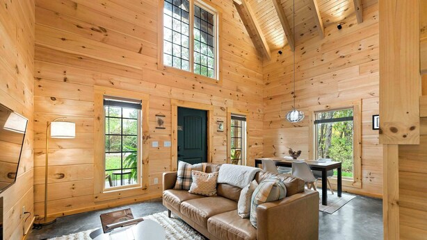 Ein gemütliches Holzhaus-Interieur mit einer Couch, einem Esstisch und einem Fernseher.