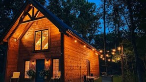 Eine Holzhütte mit einer Steinterrasse, großen Fenstern und Lichterketten.