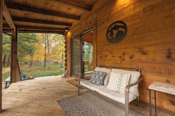 A wooden cabin with a sofa and a table, a large window, and a logo on the wall.