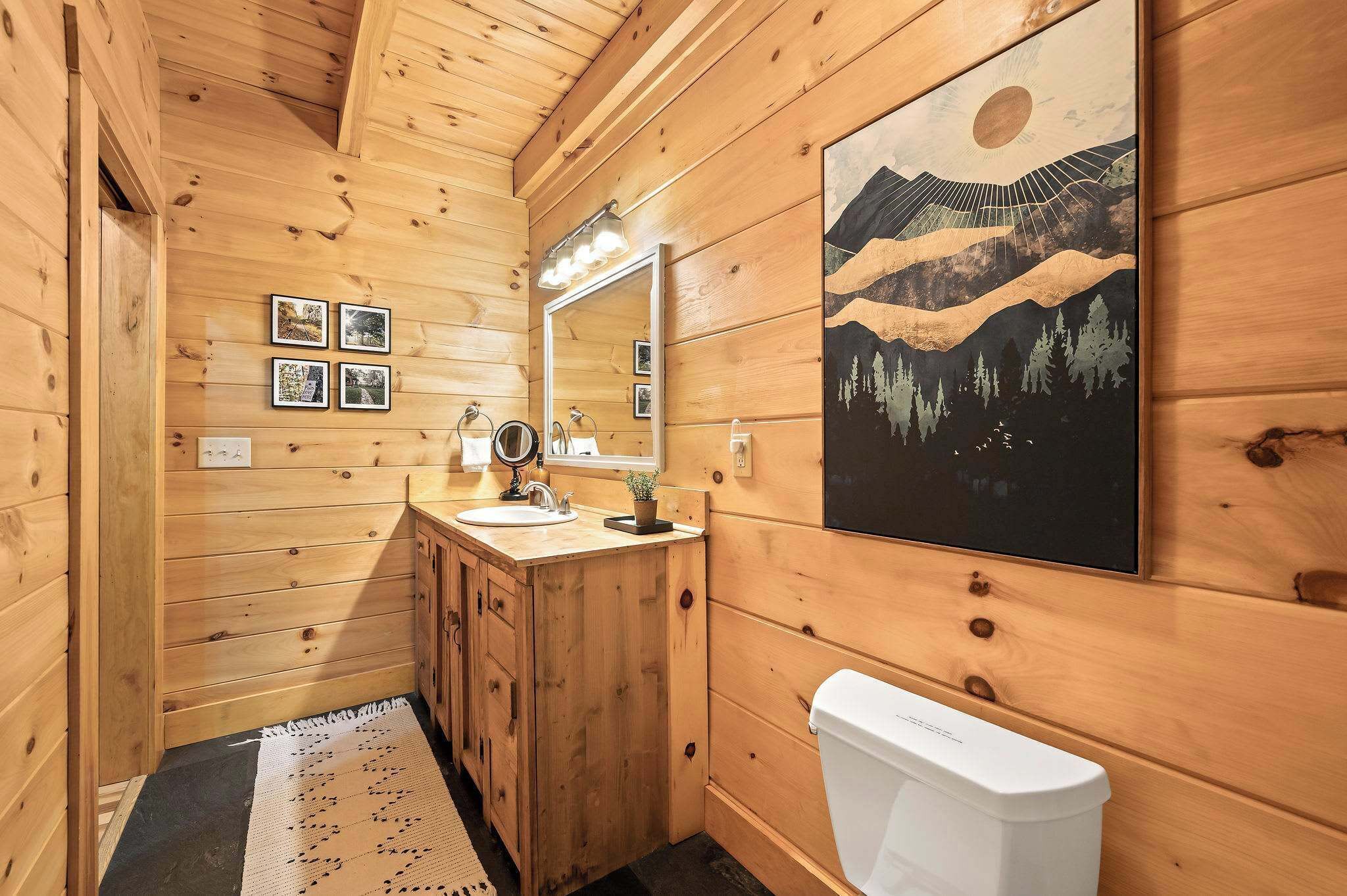 Baño de cabaña de madera con lavamanos, espejo y retrete.