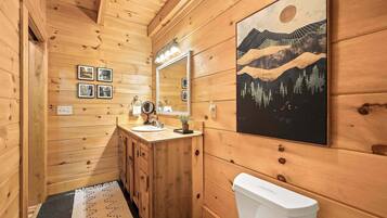 Baño de cabaña de madera con lavamanos, espejo y retrete.