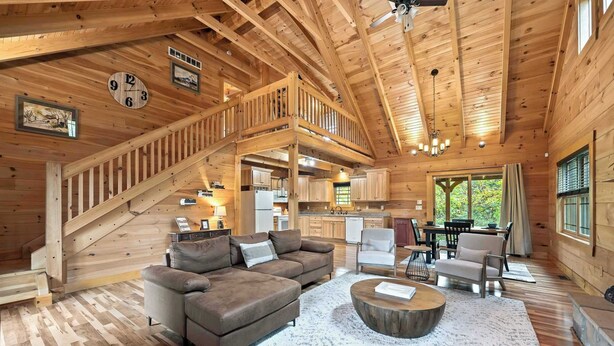 Una cabaña de madera espaciosa con habitación en altillo, comedor y cocina.