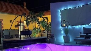 Un área de hidromasaje al aire libre con zona de estar e iluminación con luces colgantes.