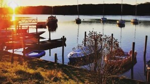Un puerto deportivo con barcos amarrados al muelle, rodeado de agua y vegetación.